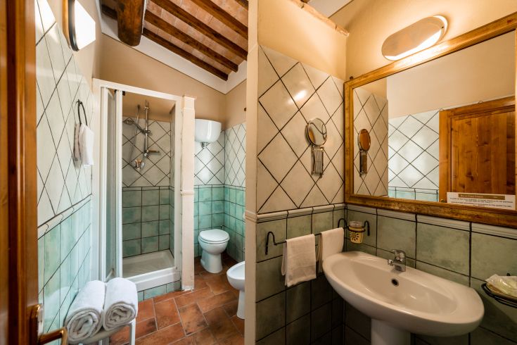 Un bagno semplice e funzionale, dotato di doccia e lavandino, in un ambiente rustico e tranquillo.