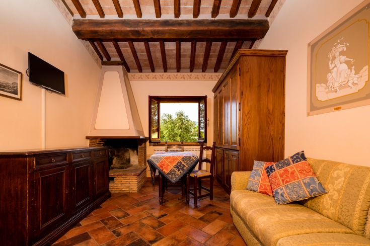 Un soggiorno semplice con camino, arredato in modo pratico e con luce naturale che entra da una finestra.