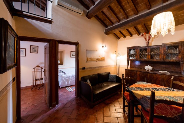 Un soggiorno semplice e luminoso con area pranzo, illuminato da una lampada d'epoca.