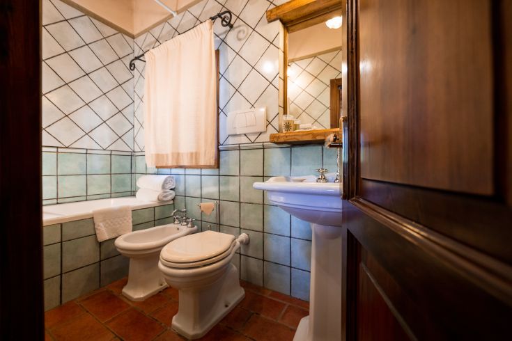 Bagno arredato con piastrelle verdi, una vasca e dettagli in legno ben curati.