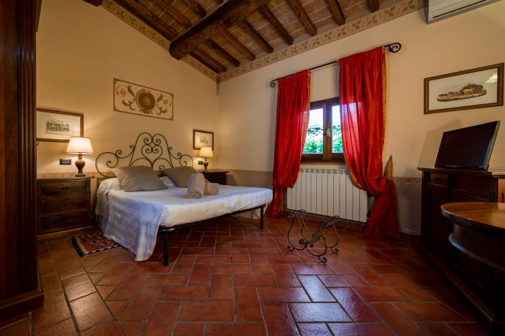 Camera semplice e ben illuminata con lettone, mobili pratici e panorama sulla campagna.