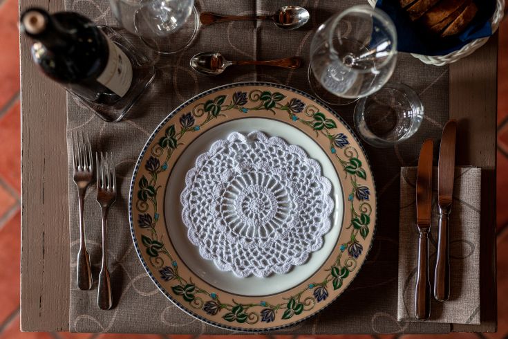 Un tavolo allestito con piatti decorativi e un bicchiere di vino è pronto per un pasto.