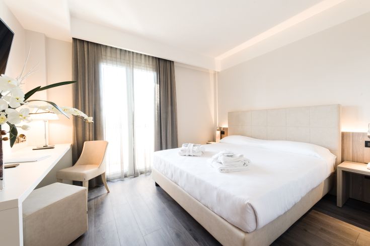 Camera semplice e ben illuminata, dotata di un letto matrimoniale e affaccio su un balcone.