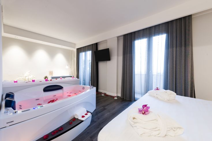 Camera accogliente con jacuzzi, arredata in modo semplice e decorata con fiori freschi, ideale per momenti di relax.