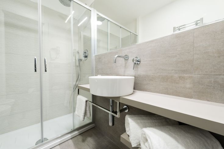 Un bagno recente e funzionale, con doccia, lavabo semplice e sanitari in tonalità tenui.