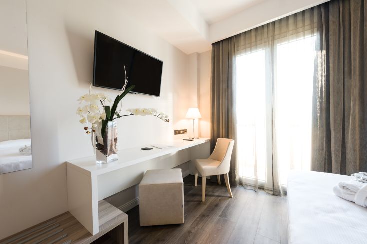 Una camera semplice con TV, scrivania e buona illuminazione naturale, adatta per un soggiorno confortevole.