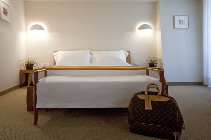 Camera accogliente con letto matrimoniale e un bagaglio posizionato accanto, un angolo rilassante.