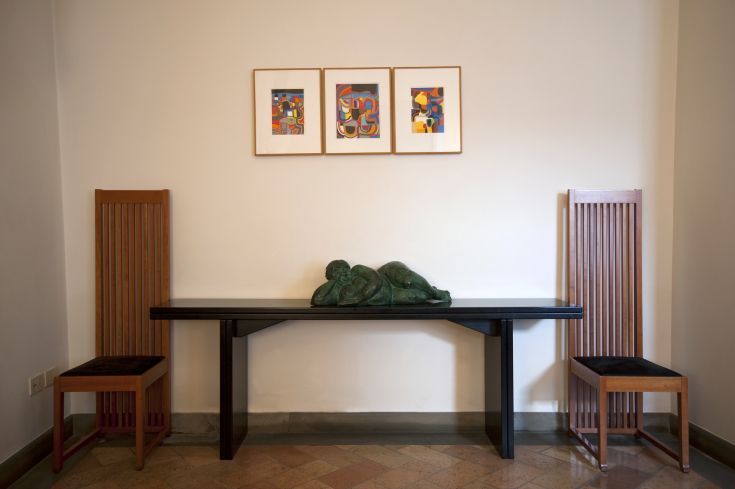 Un angolo con elementi di design e una scultura esposta su una parete. Ambiente sobrio e curato.