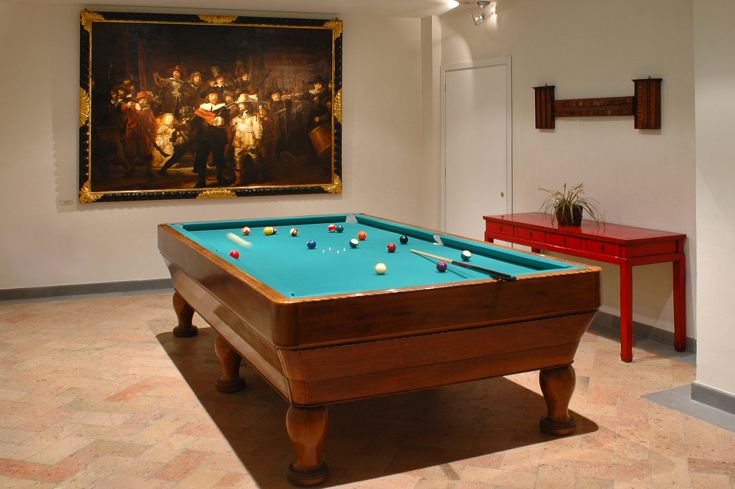 Ambiente raffinato con un tavolo da biliardo, decorato con un grande dipinto d'epoca e arredamento elegante.