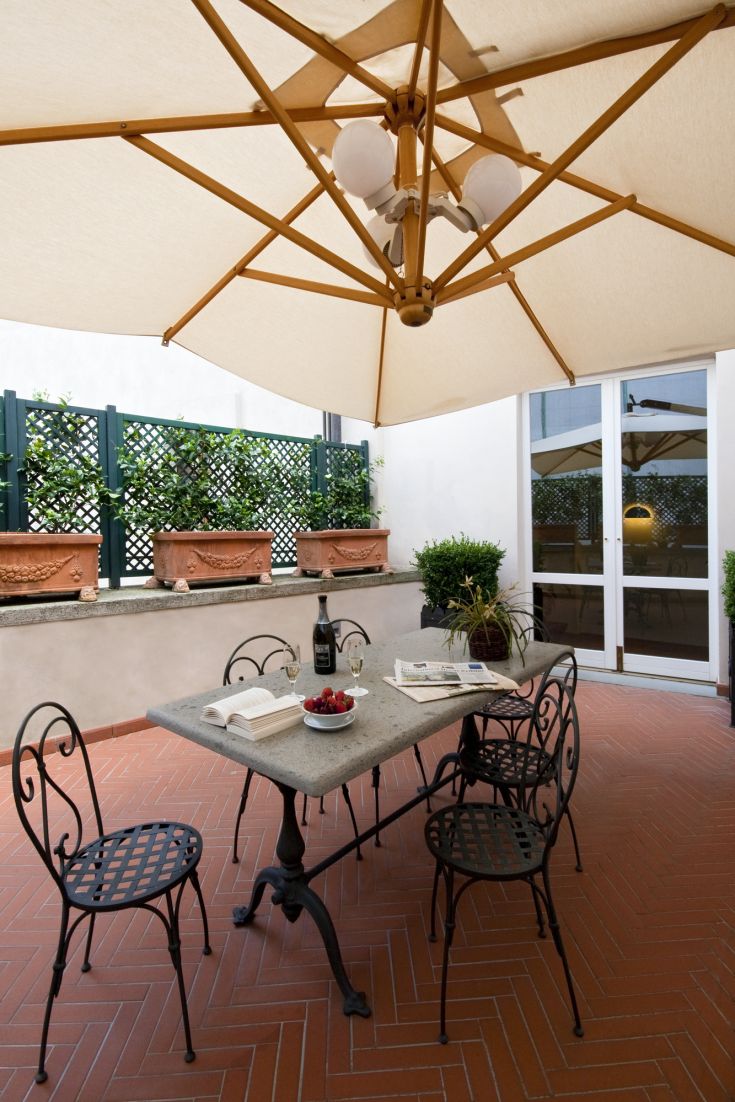 Spazio esterno con tavolo, sedie e piante, perfetto per pranzare all'aperto.