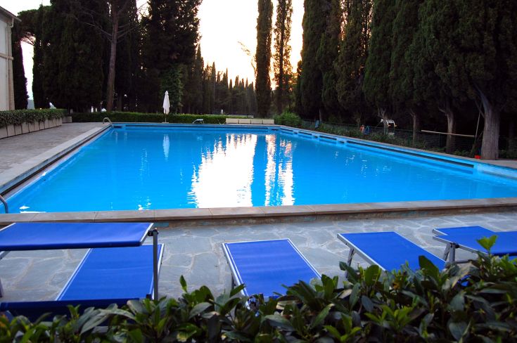 Una piscina di colore blu circondata da un ampio spazio verde, ideale per trascorrere momenti di relax all'aperto.