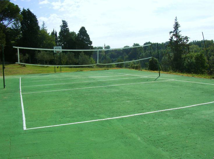 Un campo da tennis situato in un'area verde, circondato da alberi e prati.