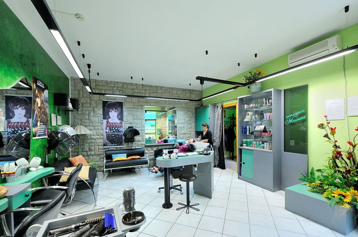 Un salone di bellezza contemporaneo con tonalità verdi e arredi confortevoli. Include una zona relax e spazi per trattamenti estetici.