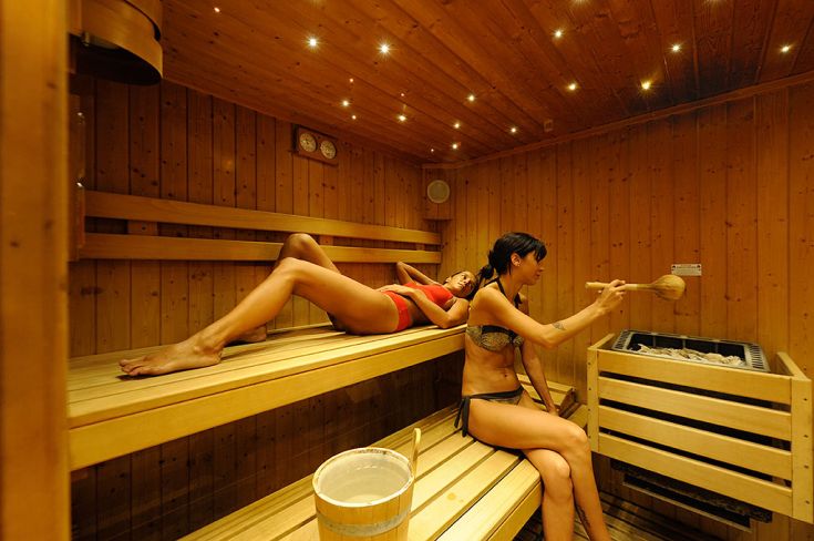 Due donne si prendono una pausa di relax in una sauna, in un ambiente caldo e confortevole.