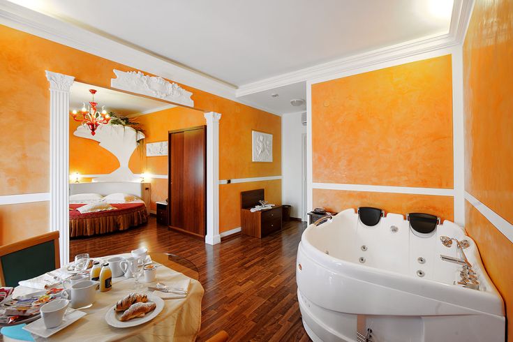 Una camera di un hotel con tonalità arancioni e dotata di vasca idromassaggio, adatta per momenti di relax.