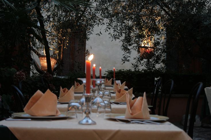 Un ristorante all'aperto con candele e tovaglie piacevoli, ideale per cene tranquille e intime.