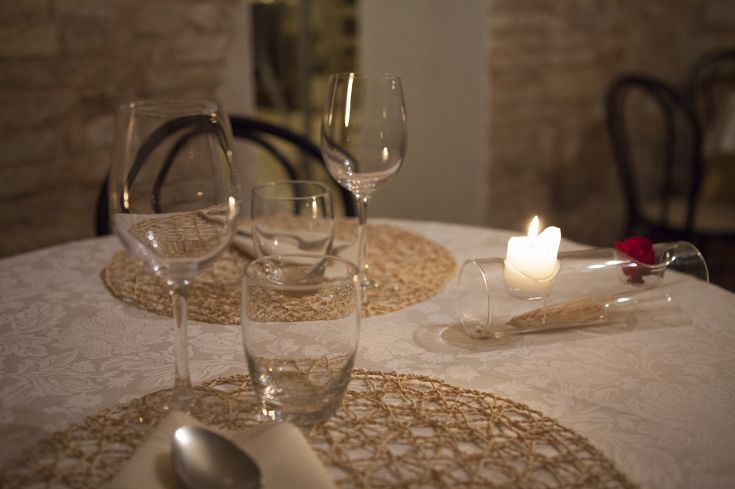 Tavolo ben apparecchiato con bicchieri e una candela, crea un'atmosfera intima.