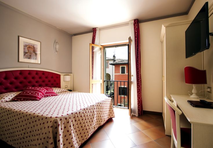 Camera semplice con letto matrimoniale, arredamento sobrio e luce naturale. Si affaccia su un'area urbana tranquilla.