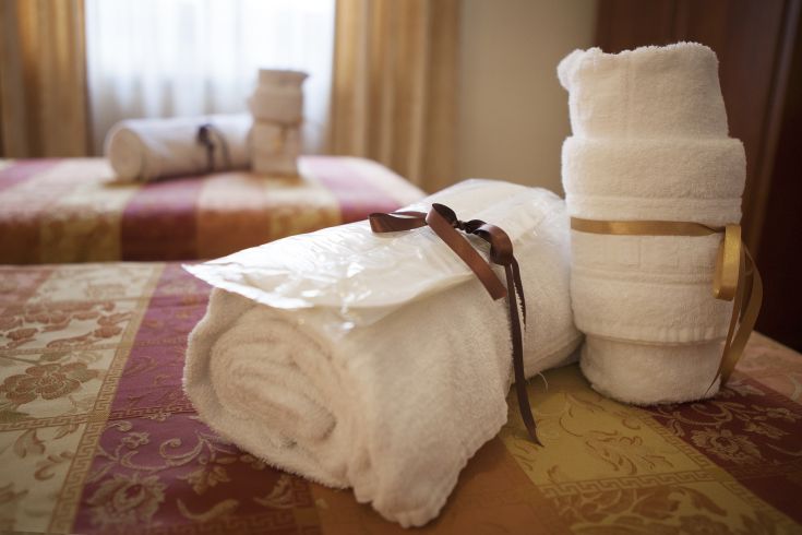 Asciugamani bianchi piegati su letti in una stanza d'albergo semplice e accogliente.