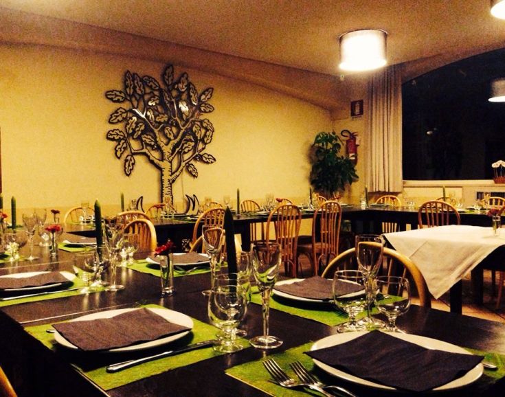 Un ristorante con tavoli apparecchiati e piante decorative che creano un'atmosfera piacevole.