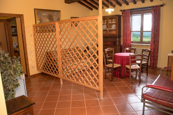 Spaziosa zona giorno con elementi in legno, affacciata sulle dolci colline umbre.