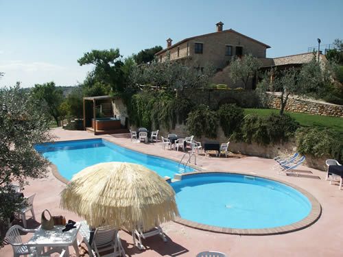 Piscina situata in un agriturismo, circondata da piante, perfetta per trascorrere momenti di relax all'aperto.