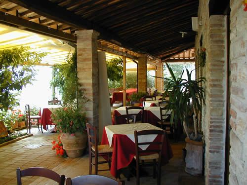 Un ristorante in stile rustico, con tavoli apparecchiati e piante verdi che contribuiscono a un'atmosfera tranquilla.