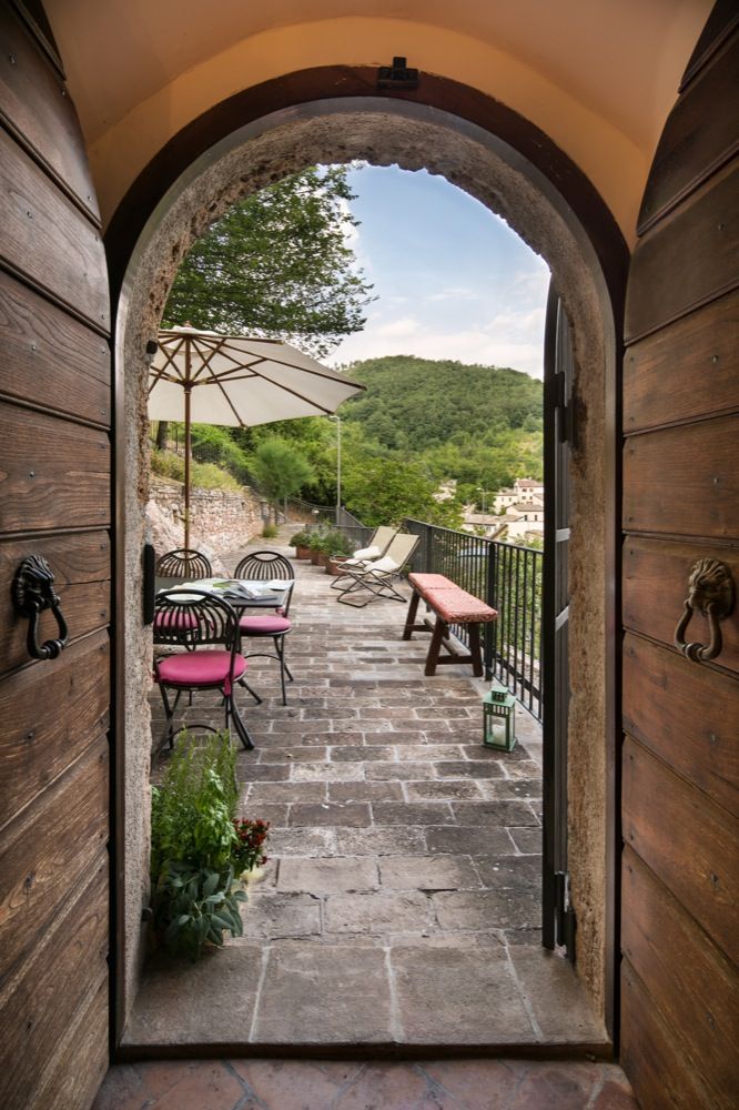 Un patio arredato con tavoli e sedie, circondato da vegetazione e con panorama sui monti circostanti, ideale per momenti tranquilli.