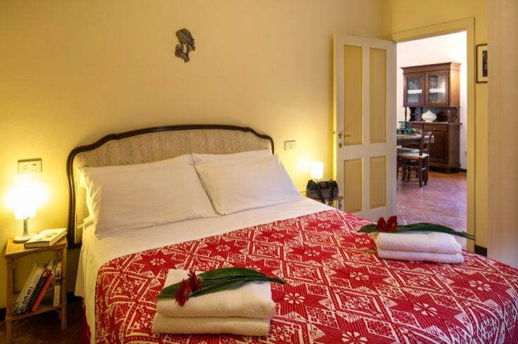 Soggiorno con letto matrimoniale, arredato con decorazioni floreali e dettagli semplici, ideale per momenti di relax.