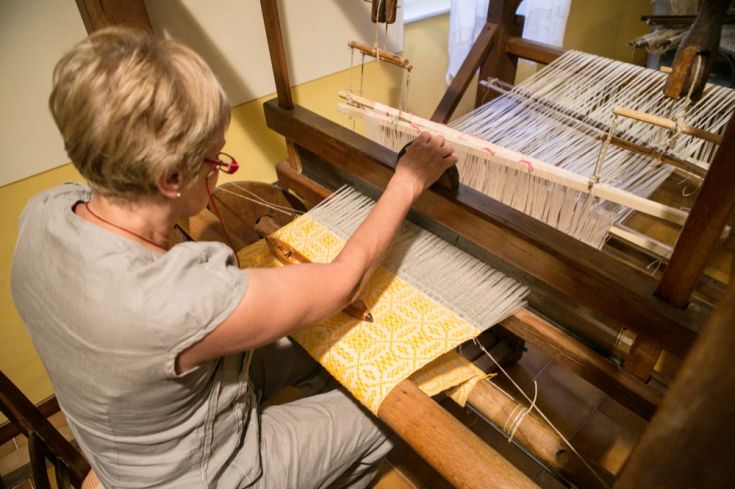 Una donna utilizza un telaio per realizzare un tessuto caratterizzato da un motivo geometrico.