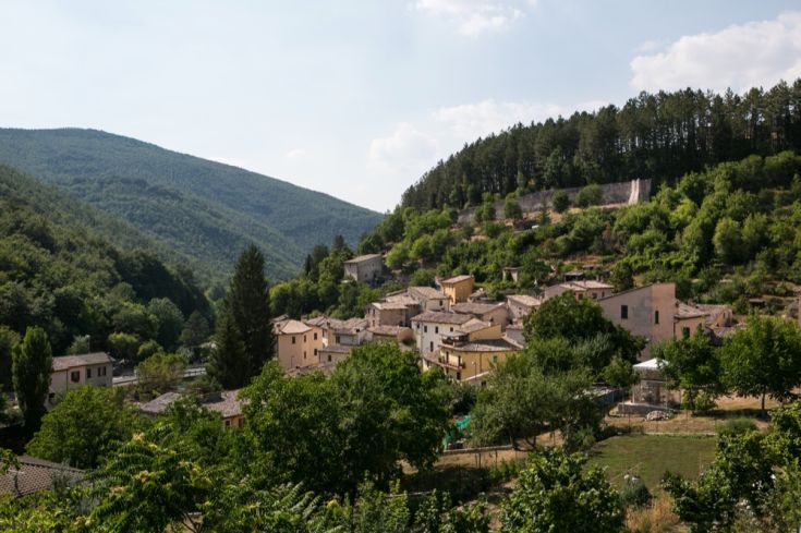 Il paese medievale di Rasiglia si trova tra colline verdi e boschi, con abitazioni caratteristiche in un ambiente sereno.