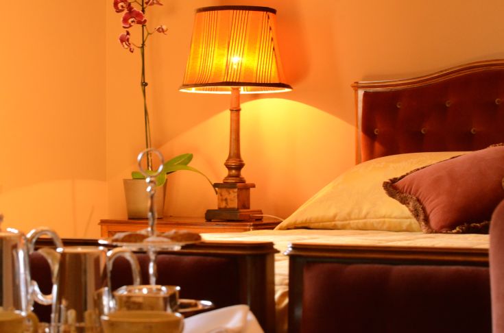 Stanza semplice con letti, illuminazione calda e arredi essenziali.