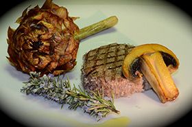 Piatto preparato con carne tenera, funghi, carciofi e rosmarino, servito con cura.
