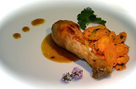 Un coscio di pollo servito con carote, decorato con erbe fresche.