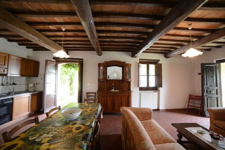 Interno semplice e confortevole di un alloggio con tavolo, cucina e decorazioni in stile rustico.