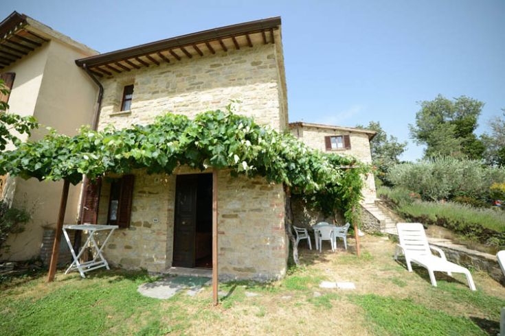 Une maison en pierre immergée dans la verdure, entourée d'arbres et de végétation luxuriante.