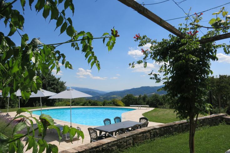 Une piscine sereine entourée d'arbres et de collines, offrant une atmosphère relaxante et naturelle.