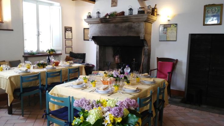 A serene agriturismo atmosphere with simply set tables and a fireplace creating a relaxing ambiance.