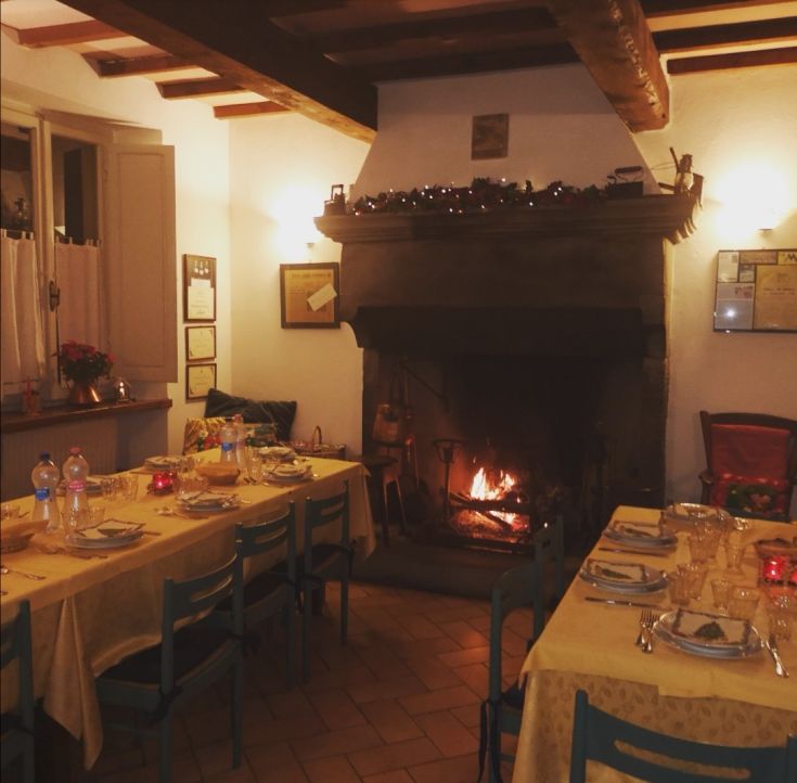 Cozy restaurant interior with neatly arranged tables and a lit fireplace, perfect for a quiet evening.