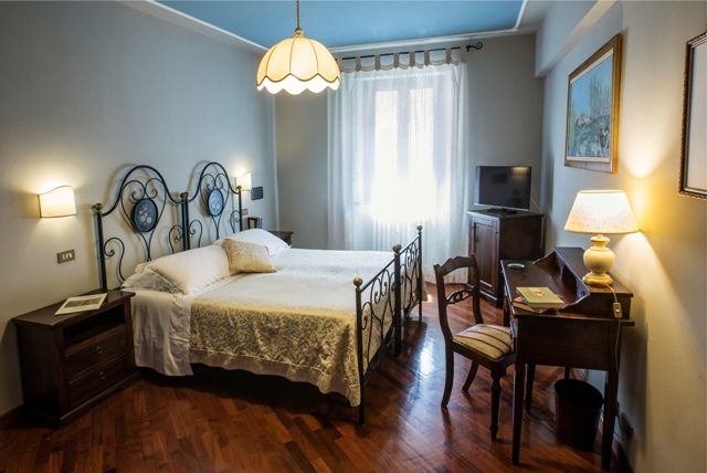 Chambre simple avec un lit double, des meubles traditionnels et de la lumière naturelle entrant par les fenêtres.