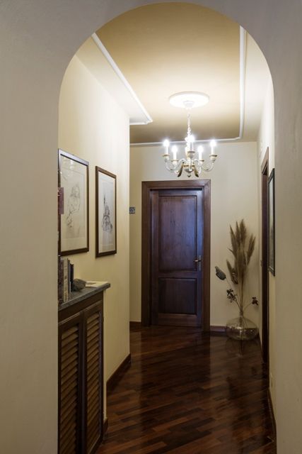 Un couloir lumineux avec des murs clairs, éclairé par un lustre central et décoré de manière simple.