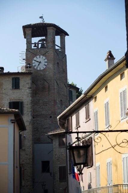 Un clocher avec une horloge, situé dans une zone historique, entouré de bâtiments traditionnels.