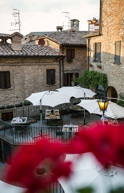 Une terrasse confortable dans un village typique, équipée de parasols et de tables pour le repas en plein air.