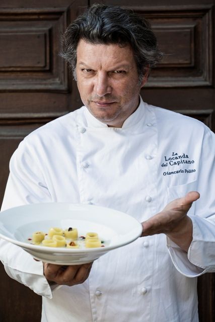 Un chef présente avec soin une assiette de pâtes préparées avec des ingrédients frais.