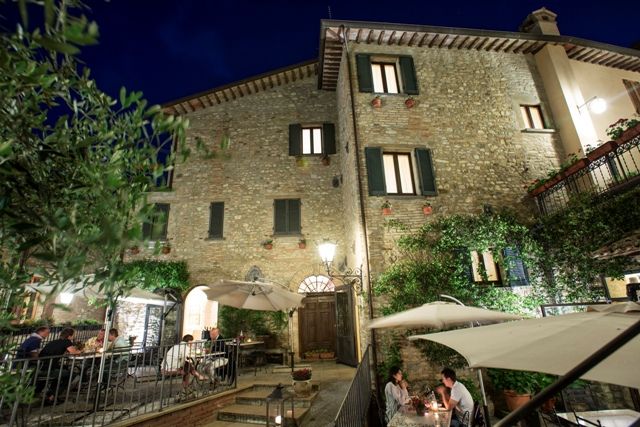 Une auberge confortable avec des tables en plein air, bien éclairée, entourée de verdure et de nature.