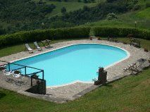 Una piscina situata in un'area verde e tranquilla, con alberi e prati circostanti.