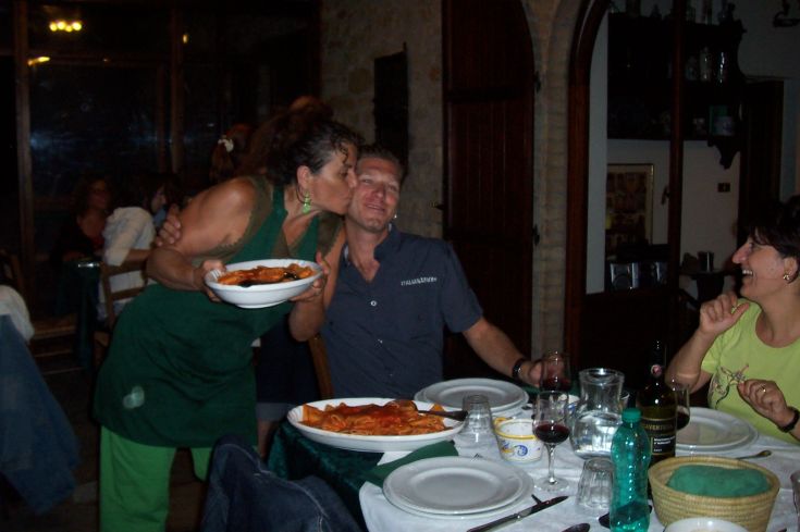 Un momento di socialità in un ristorante, con piatti di pasta fumante e sorrisi, in un ambiente accogliente.