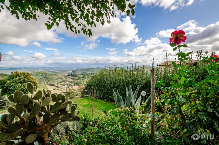 Eine Ferienbauernhof inmitten von grünen Hügeln, bunten Blumen und einem klaren Himmel, ideal zum Entspannen.