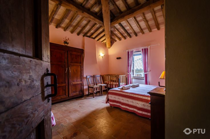 Das Innere eines charmanten Agriturismo-Zimmers mit freiliegenden Balken und dunklen Holzmöbeln.