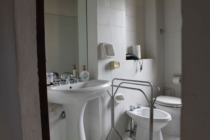 A practical and well-organized bathroom featuring modern fixtures, a sink, a mirror, and white walls.